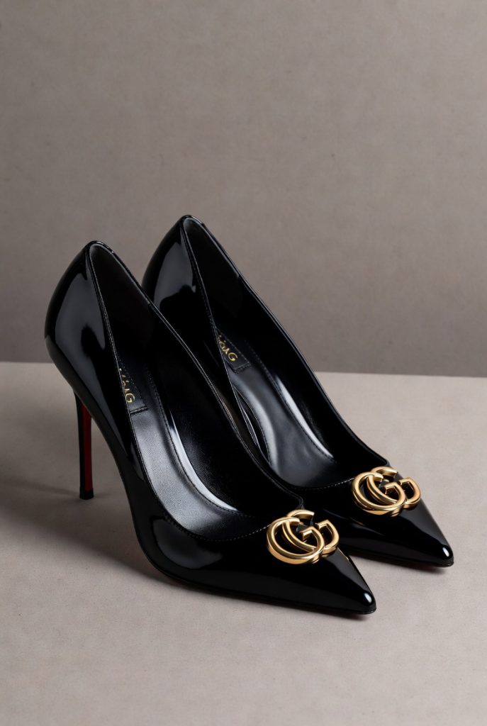 Gucci GG Marmont black patent leather stiletto heels featuring the iconic interlocking GG logo, gold-tone hardware, pointed toe design, and luxury designer craftsmanship.